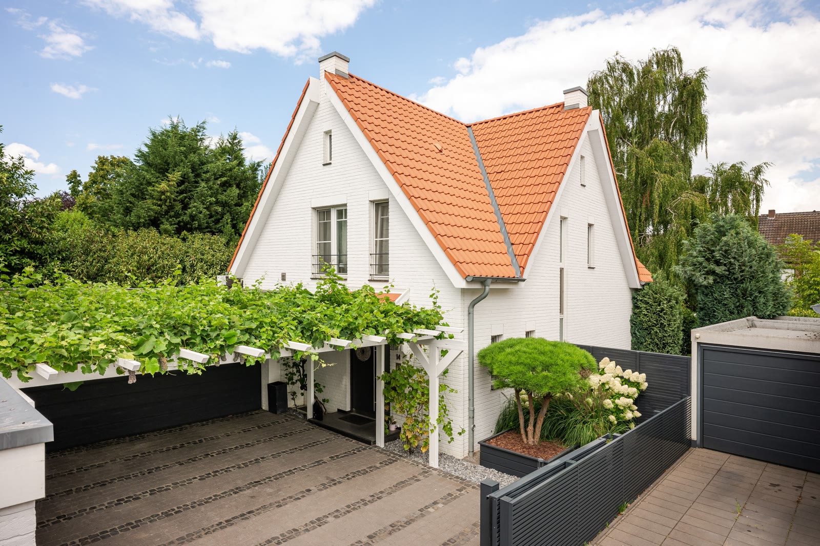 Einfamilienhaus mit weißer Fassade und Pergola – Außenansicht – Foto: Viktor Gurov