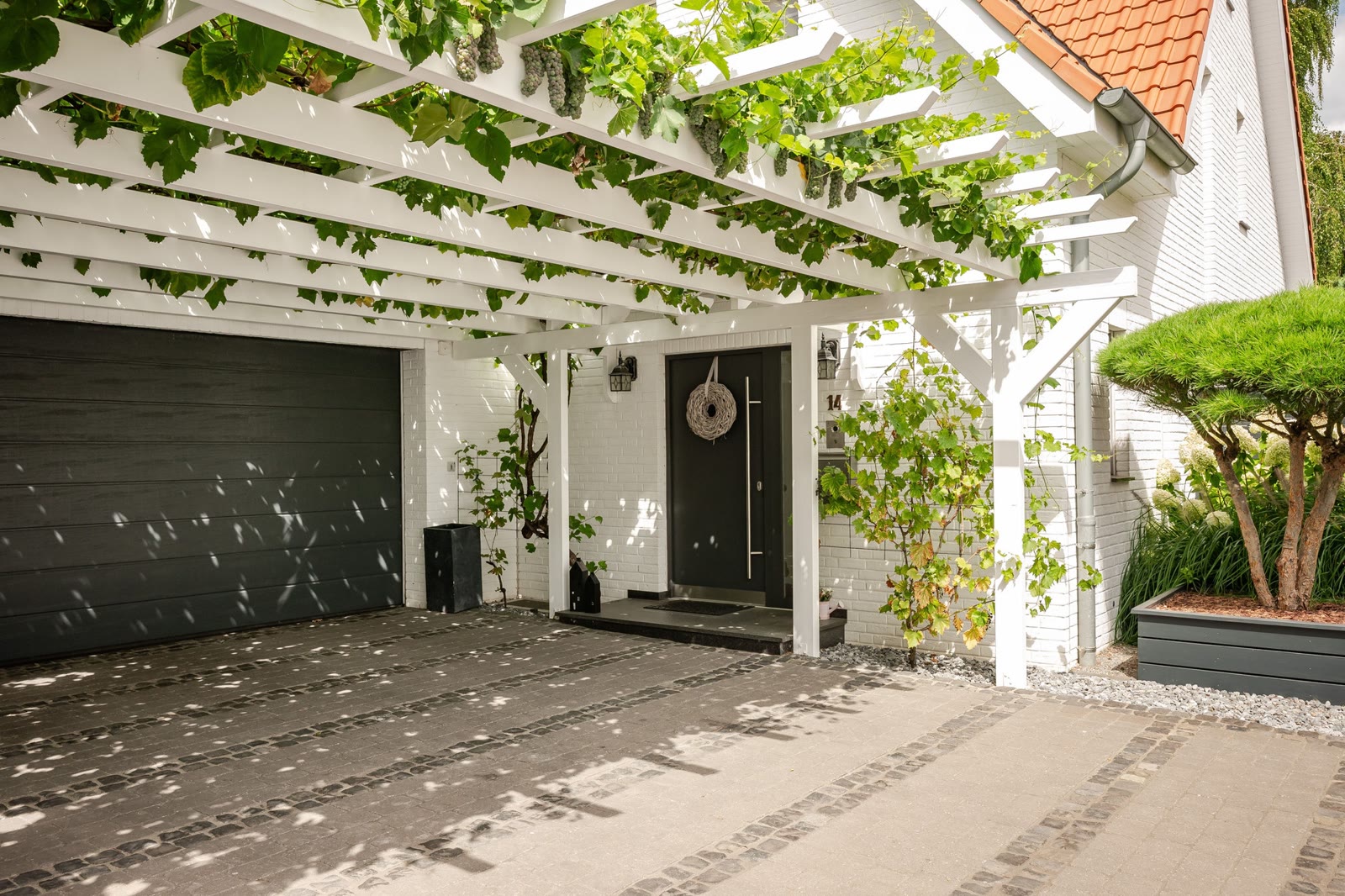 Hofeinfahrt mit begrünter Pergola und Eingang – Foto: Viktor Gurov