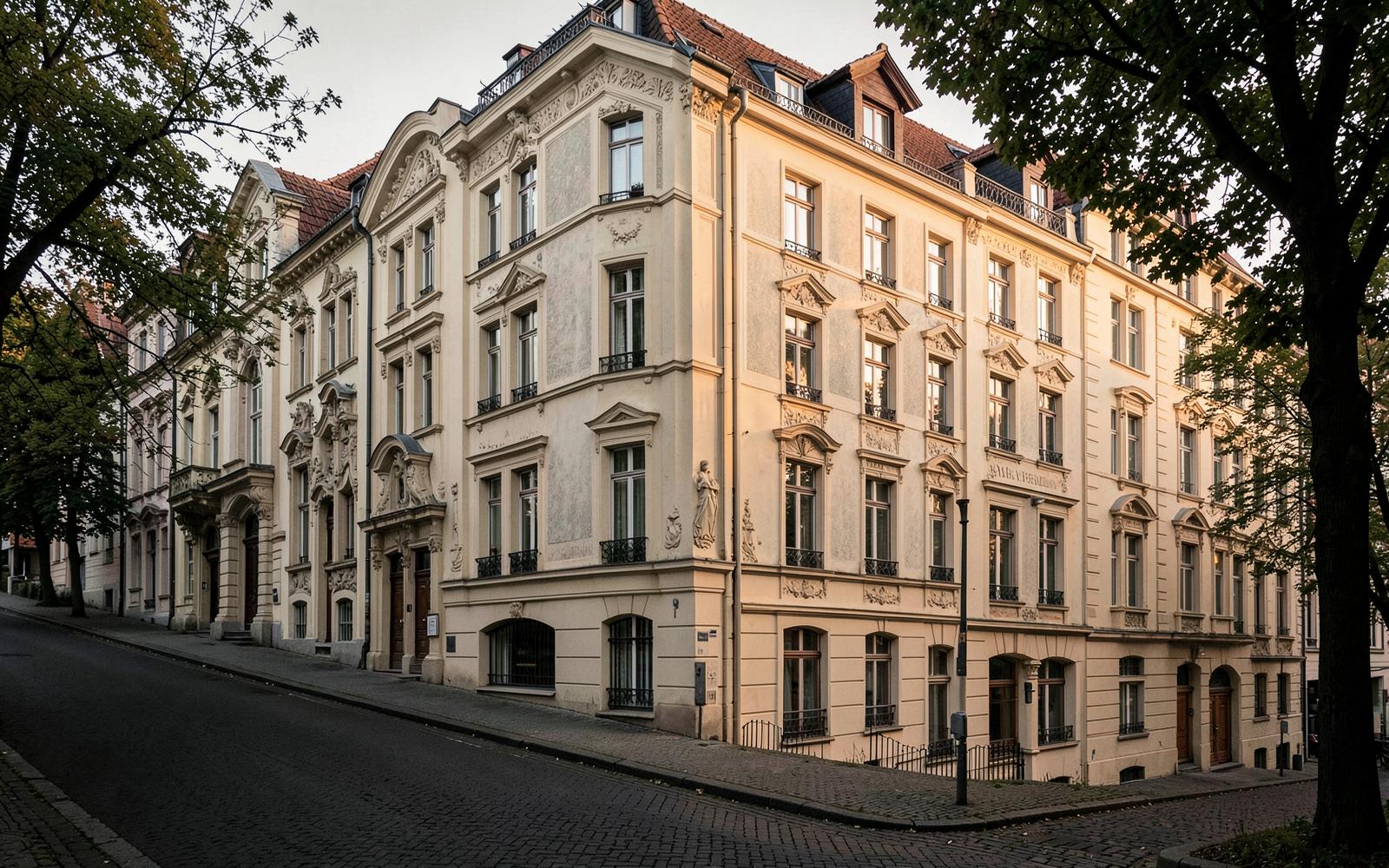 Sanierte Gründerzeit-Eckhäuser mit Stuckfassaden an einer ruhigen, baumbestandenen Straße im Abendlicht