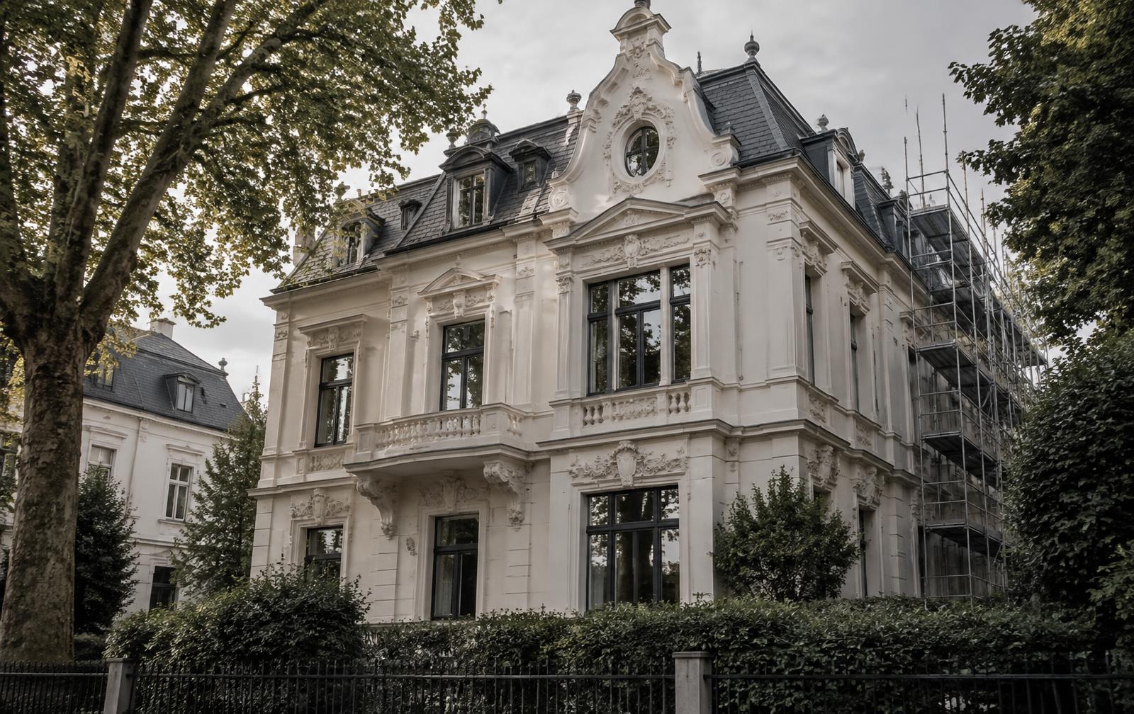 Denkmalgeschützte Gründerzeitvilla in Düsseldorf mit restaurierter Stuckfassade, Schieferdach und Gerüst an der Seitenfassade