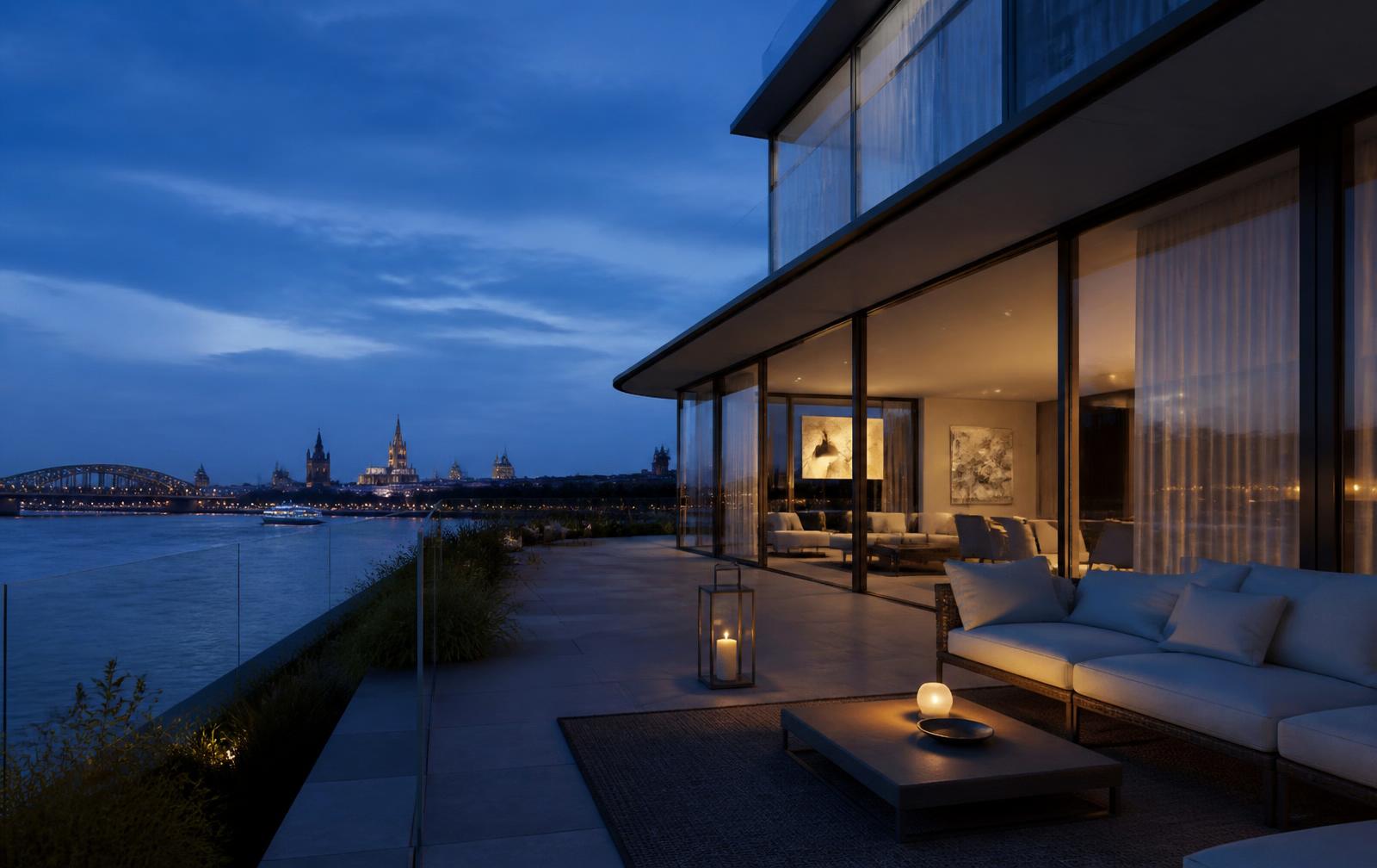 Terrasse eines modernen Hauses mit raumhohen Glasfronten und direktem Blick auf den Rhein und die Düsseldorfer Skyline zur blauen Stunde