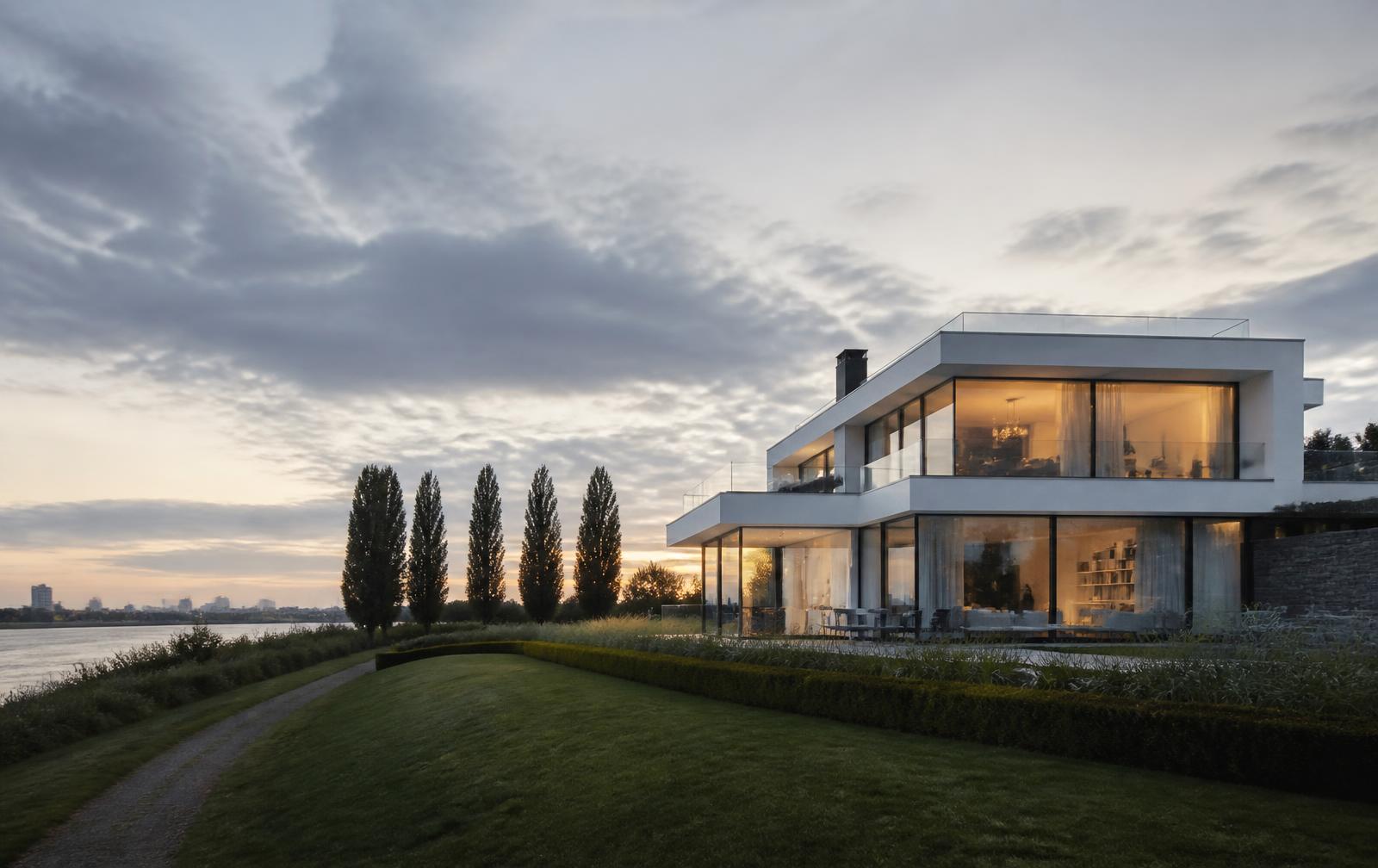 Moderne weiße Villa mit großen Glasflächen am Rheindeich in Düsseldorf-Lörick, Pappeln und Wiese im Abendlicht